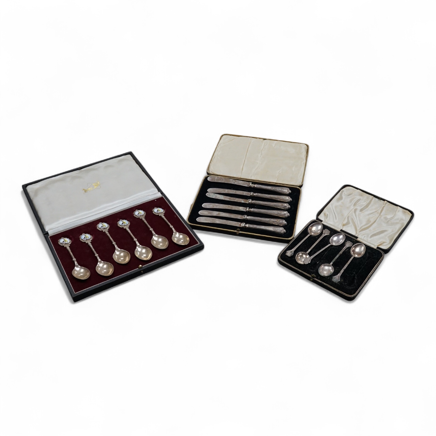 A cased set of six Elizabeth II silver teaspoons, the enamelled terminals decorated with a jockey in racing colours, maker JJW, Birmingham, 1978, together with a cased set of five (ex six) silver teaspoons and a cased se